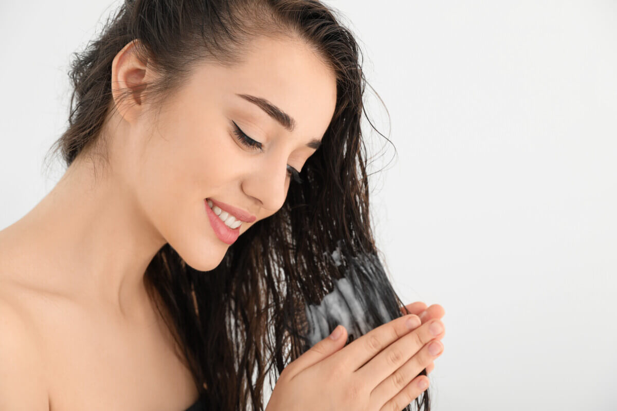 A woman applying conditioner to dry hair ends